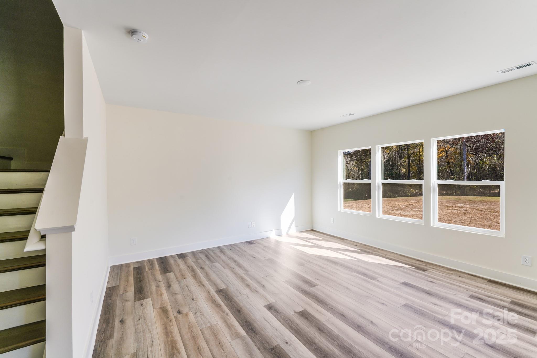 212 Sugar Hill Road Troutman, NC 28166 - Photo 11 of 47 a view of an empty room with wooden floor and windows