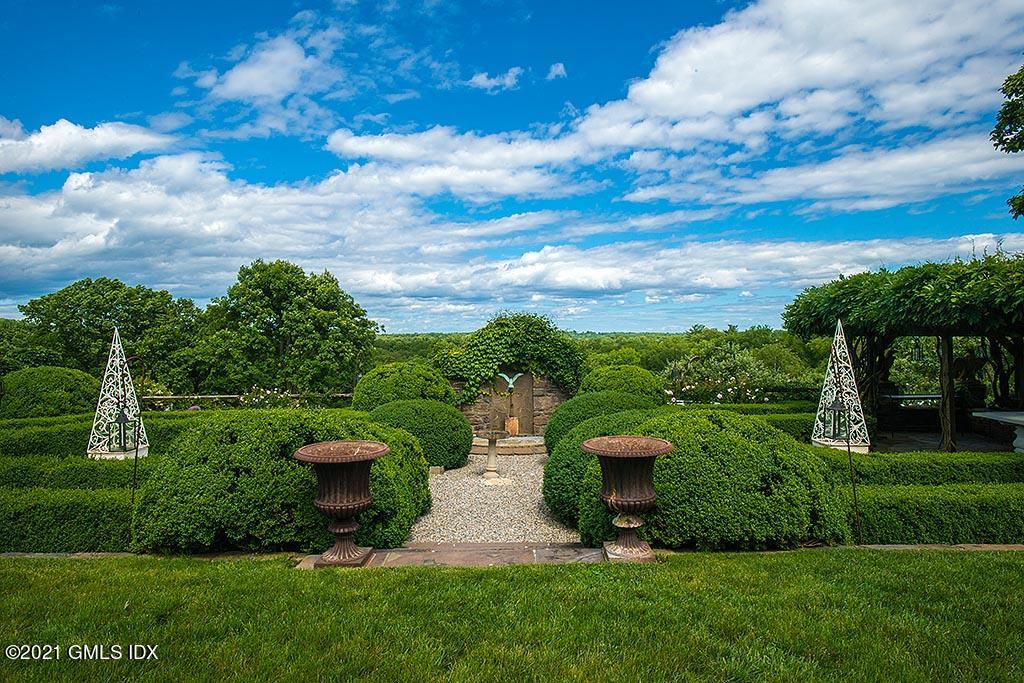 591 Riversville Road Greenwich, CT 06831 - Photo 33 of 79 a view of a garden with lawn chairs plants and large tree