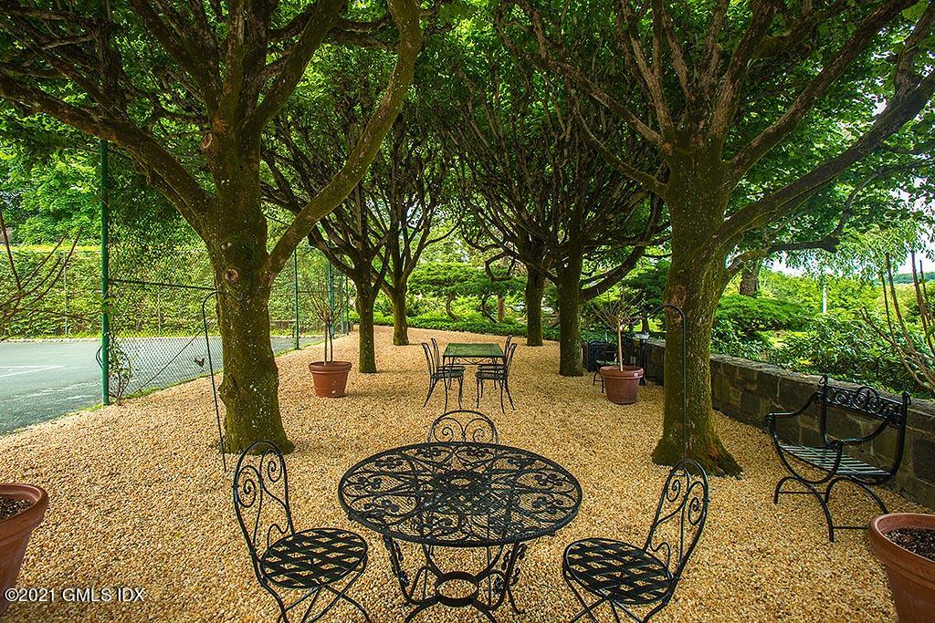 591 Riversville Road Greenwich, CT 06831 - Photo 48 of 79 a view of a patio with table and chairs potted plants and large tree