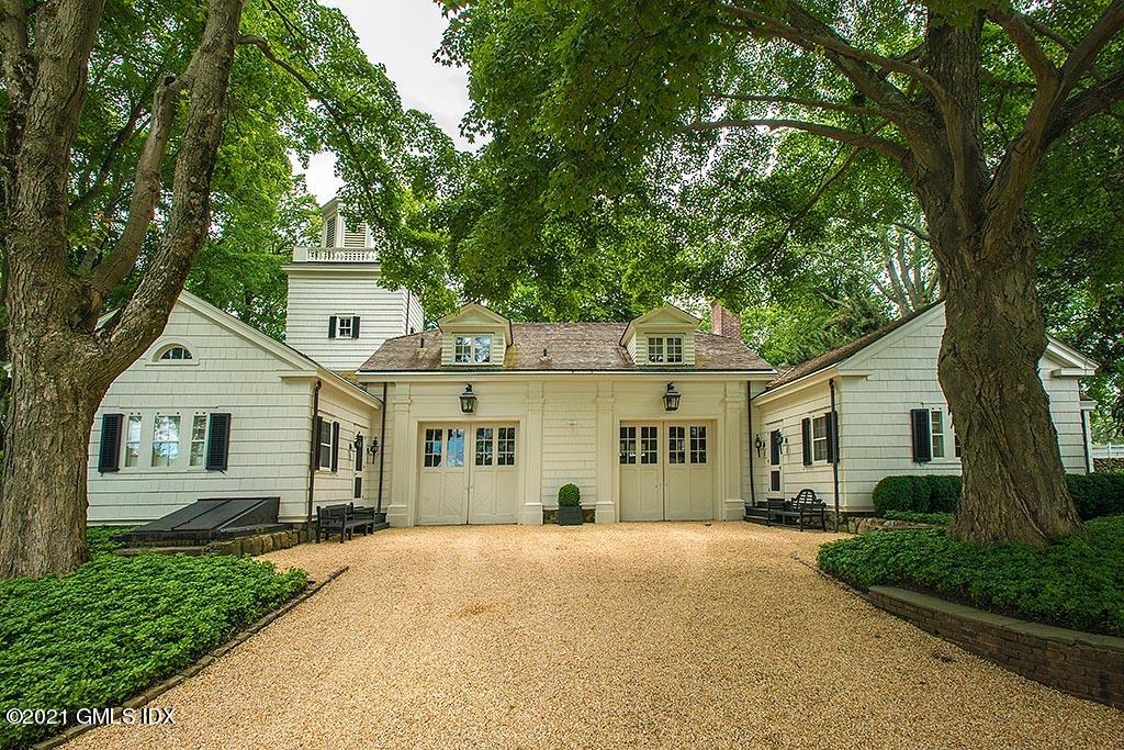 591 Riversville Road Greenwich, CT 06831 - Photo 77 of 79 a view of a white house next to a yard with plants and large trees