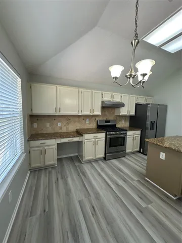 a large kitchen with granite countertop a stove and cabinets