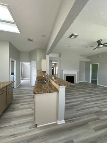 a large white kitchen with granite countertop a stove and a wooden floor