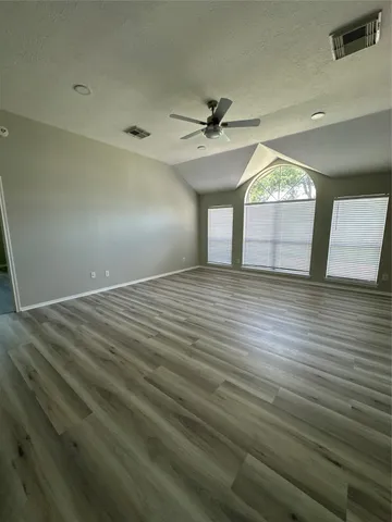 an empty room with wooden floor and windows