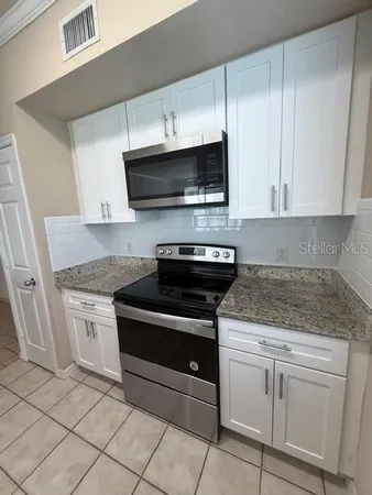 a kitchen with granite countertop white cabinets and appliances