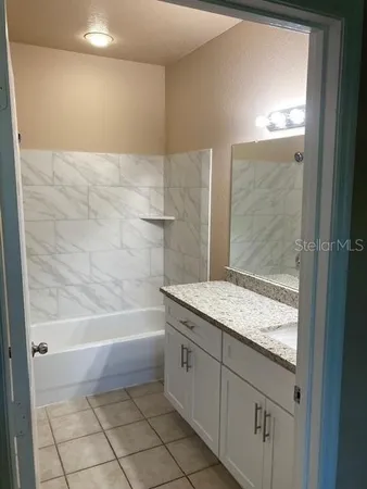 a bathroom with a granite countertop sink a toilet and bathtub