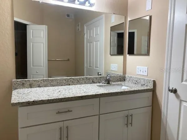 a bathroom with a granite countertop sink and a mirror