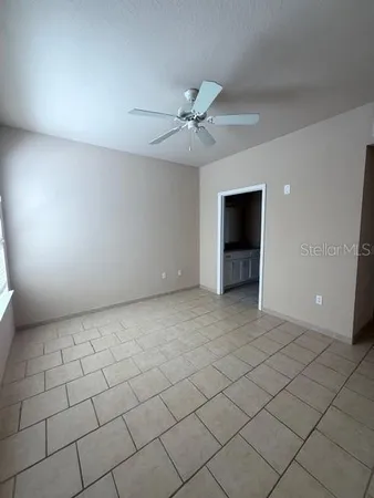 an empty room with a ceiling fan and a bathroom
