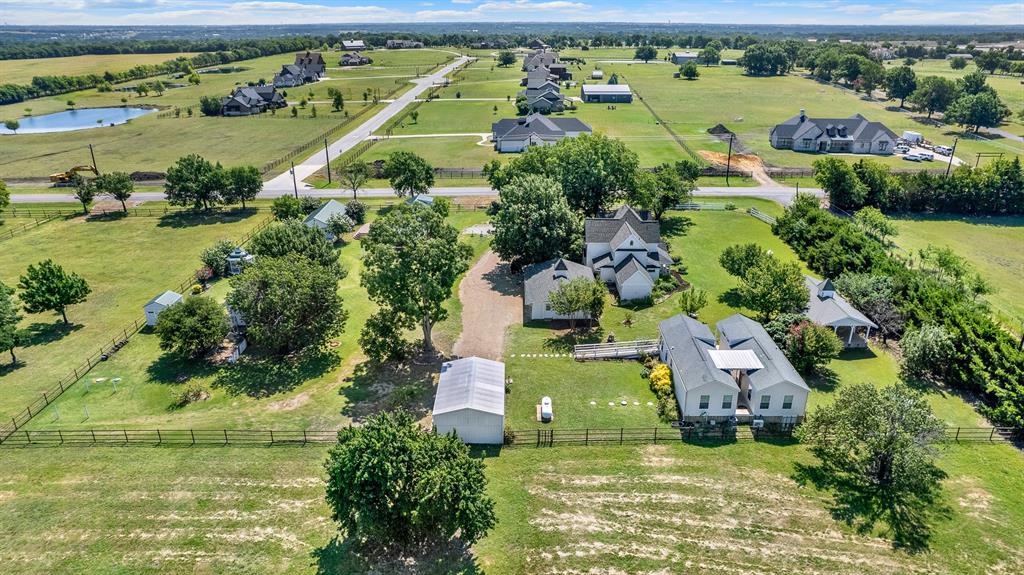 1425 Lone Star Road Celina, TX 75009 - Photo 39 of 40 This aerial showcases the timeless architecture of the beautifully restored historic residence, nestled beneath a canopy of mature trees. The wraparound porch, thoughtfully landscaped grounds, and seamless blend of original character with modern updates make this home the centerpiece of the estate. Positioned on a spacious corner lot in an area of newer luxury acreage properties, it offers both historic charm and enduring value.
