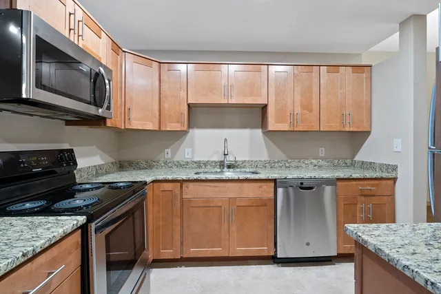 a kitchen with granite countertop a sink stove and microwave