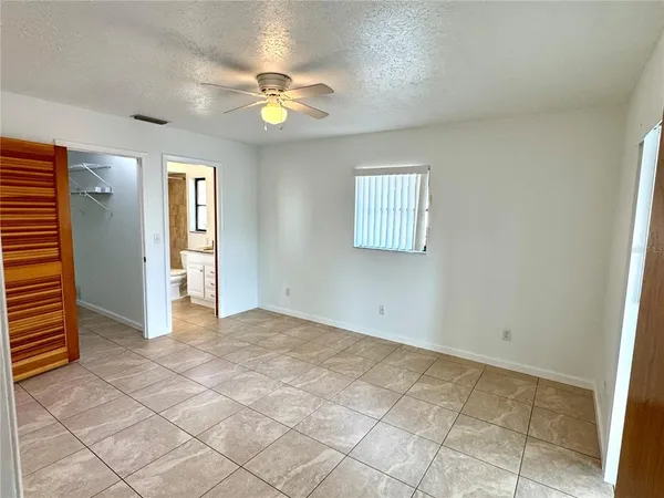 an empty room with chandelier fan and windows