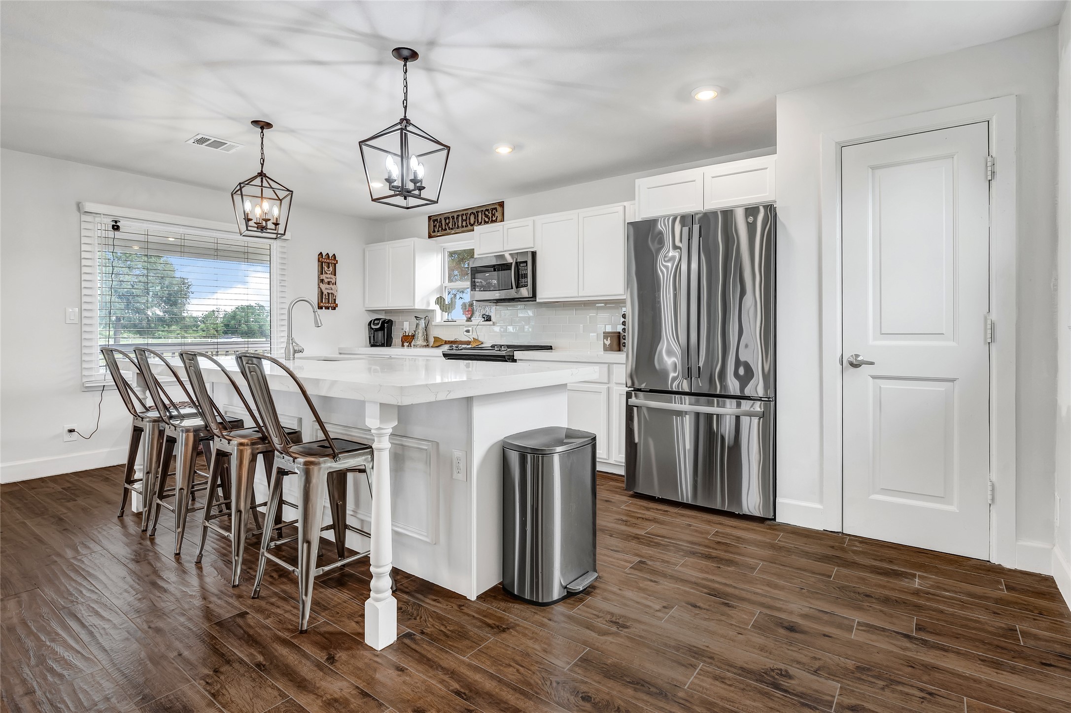 868 Lisa May Road Bellville, TX 77418 - Photo 3 of 39 Bright kitchen featuring pristine white cabinets, quartz countertops, and a spacious eat-in island, perfect for cooking and casual gatherings.