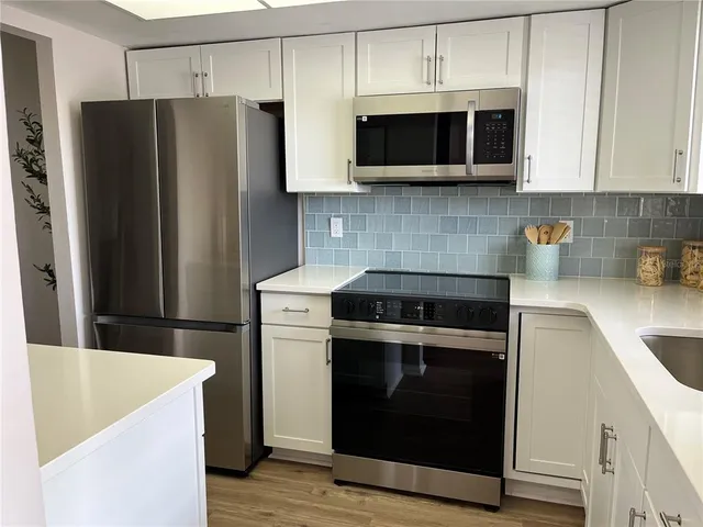 a kitchen with stainless steel appliances a stove a microwave a sink and cabinets