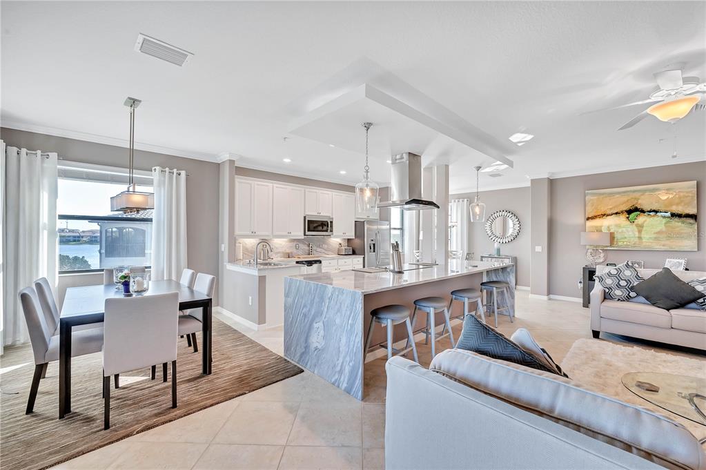 5815 Wake Forest Run, Unit 103 Lakewood Ranch, FL 34211 - Photo 11 of 63 a living room with stainless steel appliances kitchen island granite countertop furniture and a wooden floor