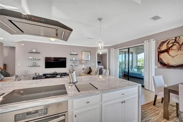 a living room with stainless steel appliances kitchen island granite countertop a refrigerator a stove a sink a dining table and chairs with wooden floor