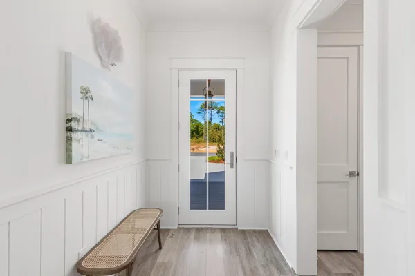 a view of a hallway with wooden floor and a bathroom