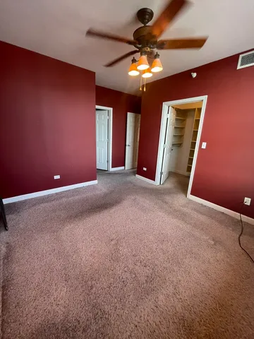 a view of an empty room with a chandelier fan