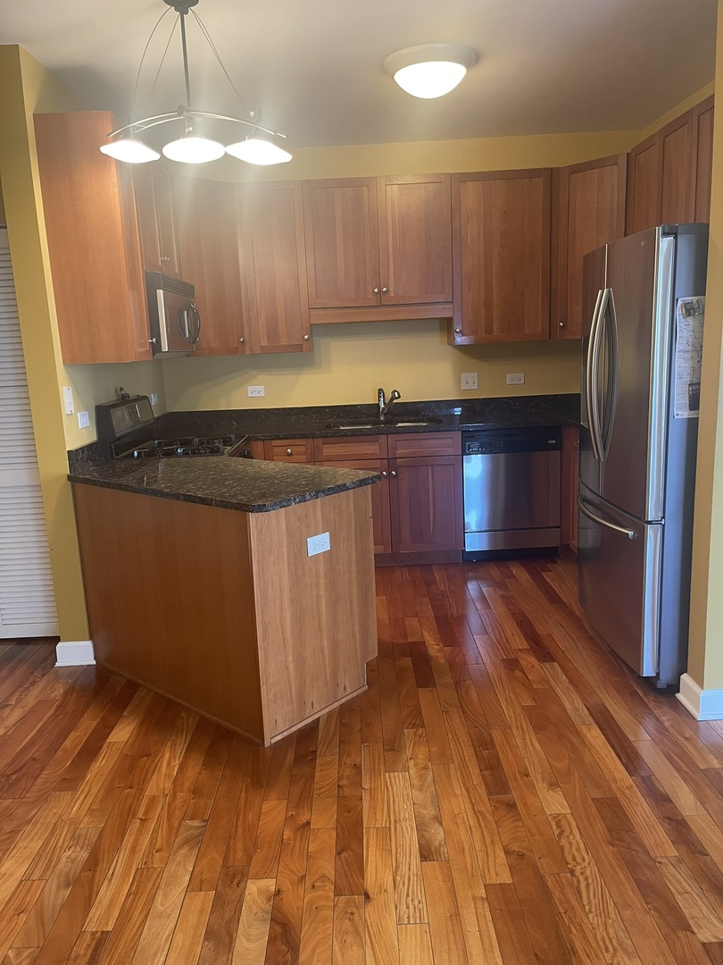 1101 South State Street, Unit 2104 Chicago, IL 60605 - Photo 3 of 37 a kitchen with granite countertop a stove a refrigerator and wooden floor