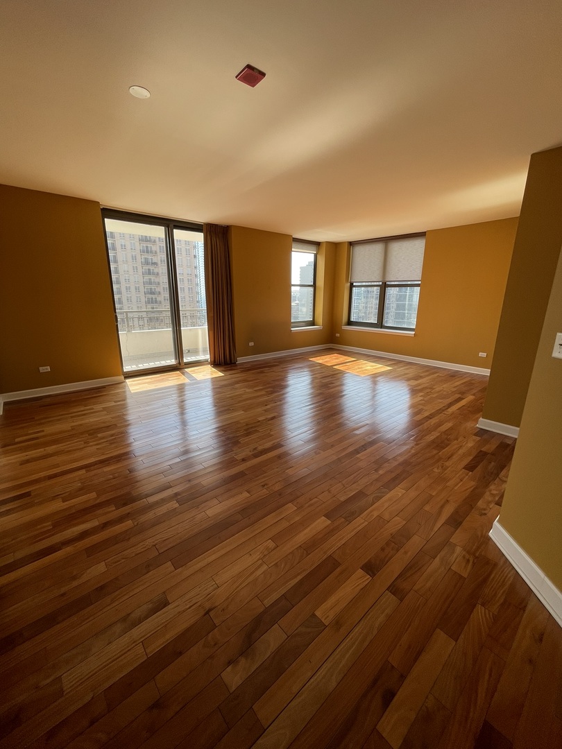 1101 South State Street, Unit 2104 Chicago, IL 60605 - Photo 6 of 37 an empty room with wooden floor and windows