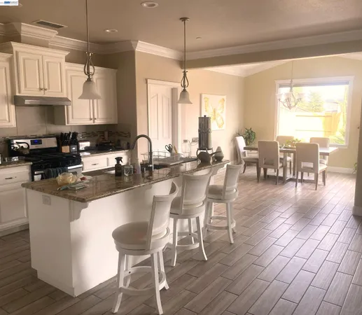 a kitchen with stainless steel appliances granite countertop a stove a sink a dining table and chairs with wooden floor