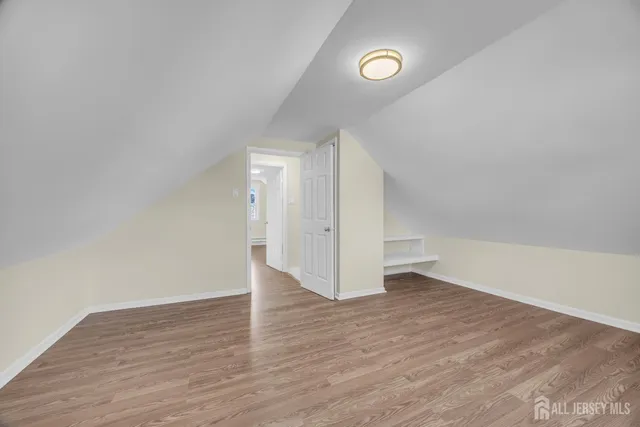 a view of an empty room with wooden floor and closet