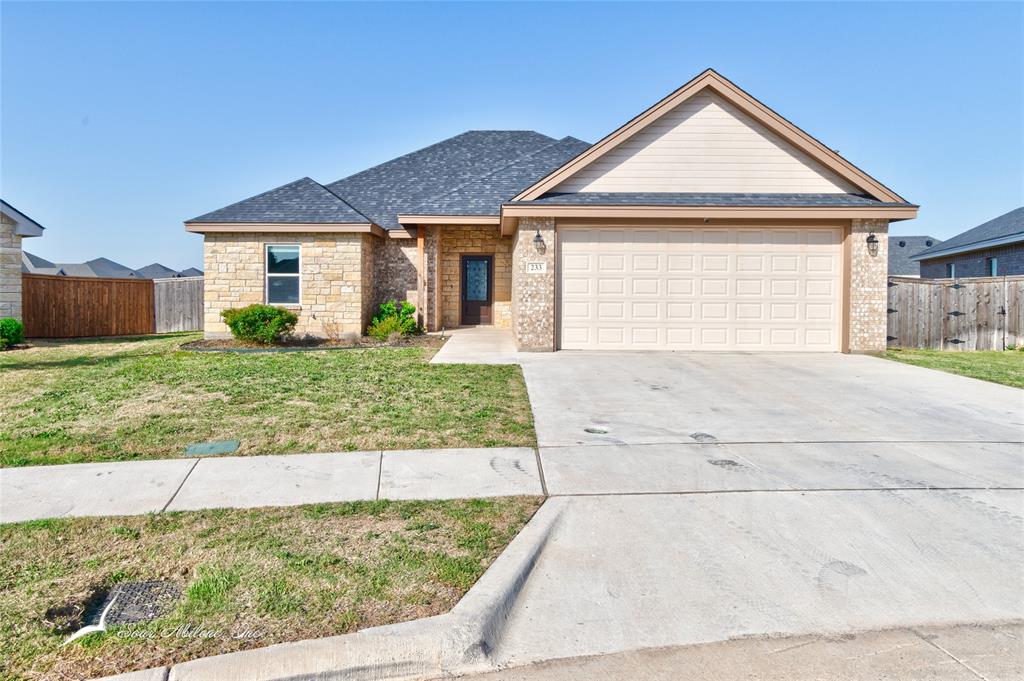 Single story home with an attached garage, driveway, fence, and a front lawn