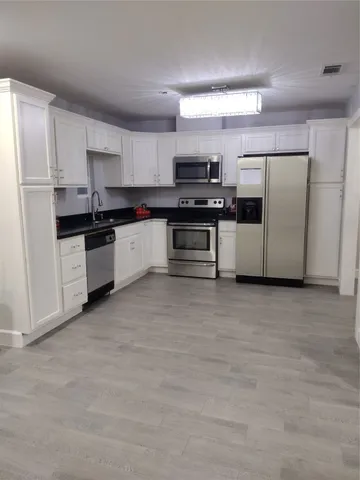 a kitchen with stainless steel appliances a refrigerator a stove a sink and white cabinets