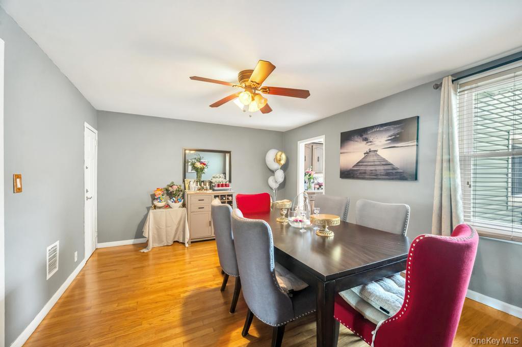 89-13 84th Street Queens, NY 11421 - Photo 15 of 34 Dining area featuring wood-finish flooring, a ceiling fan with light fixture, and a window with horizontal blinds and curtains