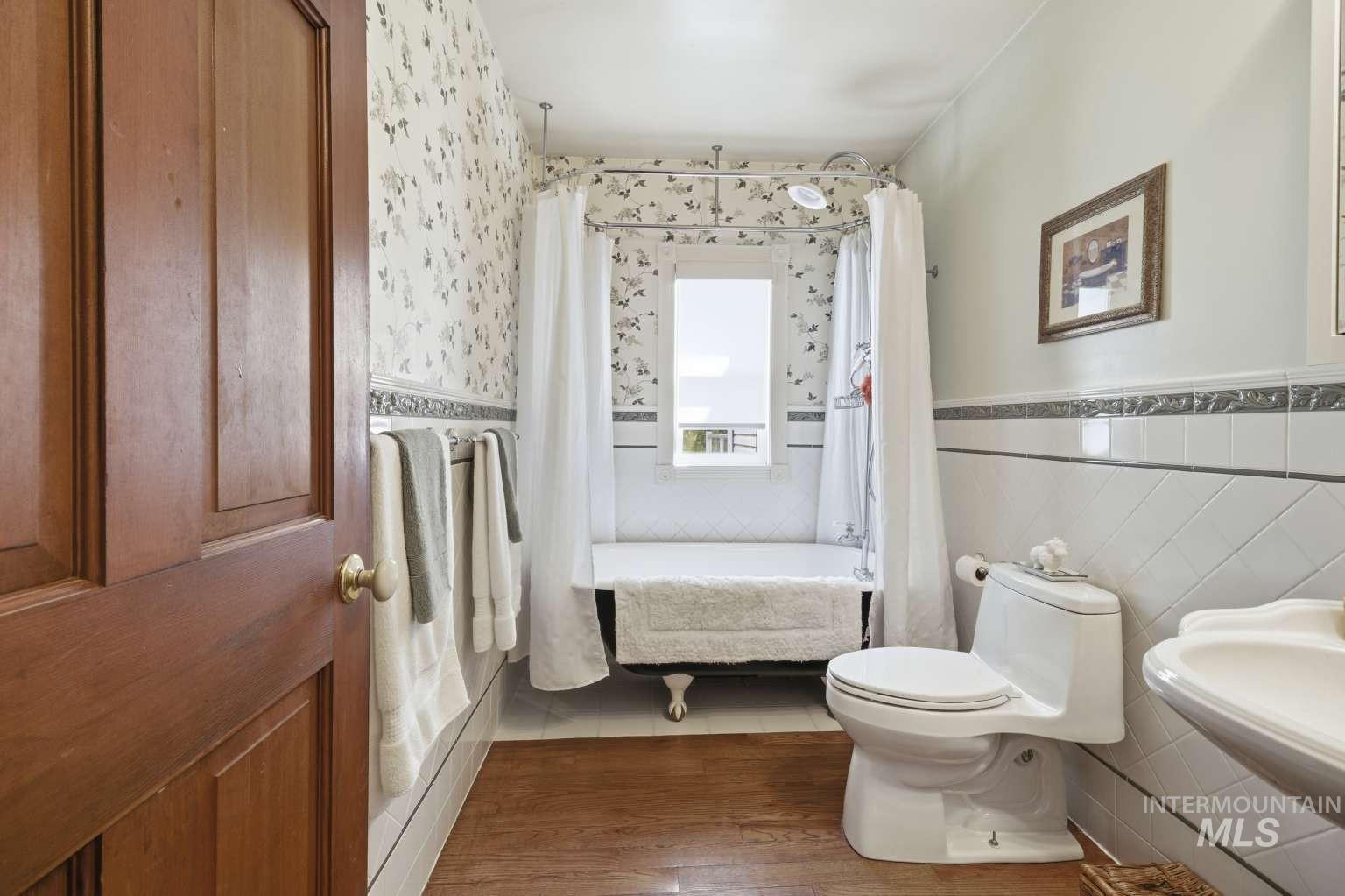 901 Main Street Kendrick, ID 83537 - Photo 24 of 50 Bathroom with wood-finish flooring, a freestanding clawfoot tub, and a window