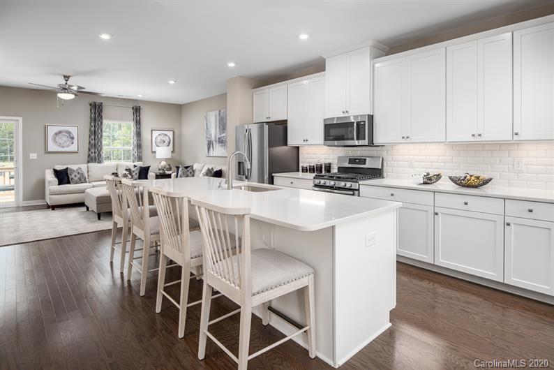 910 Portrush Lane, Unit 1015B Tega Cay, SC 29708 - Photo 2 of 8 a kitchen with stainless steel appliances a table chairs refrigerator microwave and cabinets