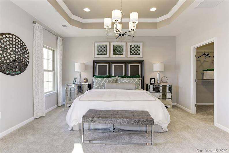 910 Portrush Lane, Unit 1015B Tega Cay, SC 29708 - Photo 4 of 8 a large bed sitting in a bedroom next to a window and a chandelier