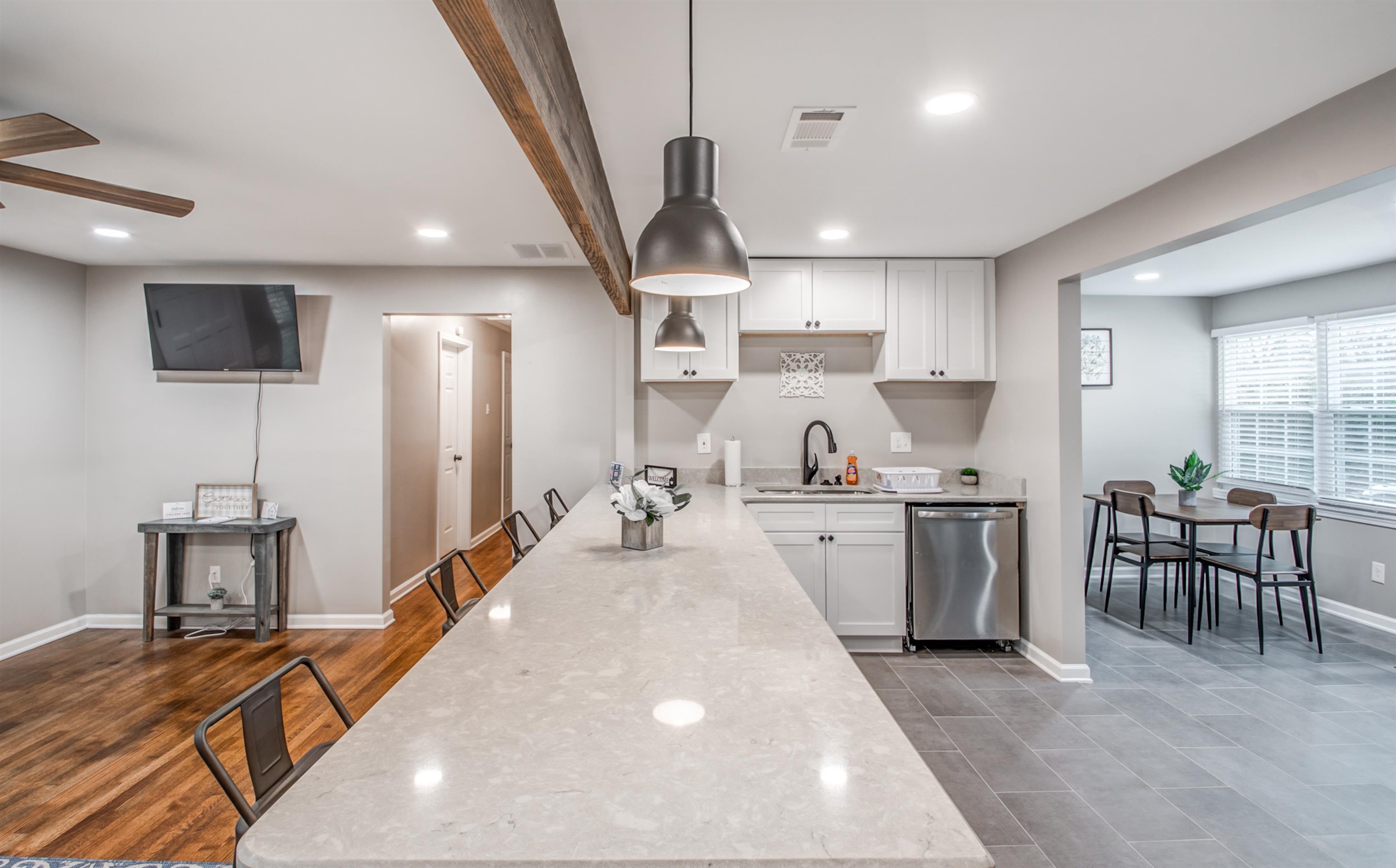 1277 Wellsville Road Memphis, TN 38117 - Photo 1 of 39 Kitchen featuring a breakfast bar, white cabinets, light stone counters, stainless steel dishwasher, and ceiling fan