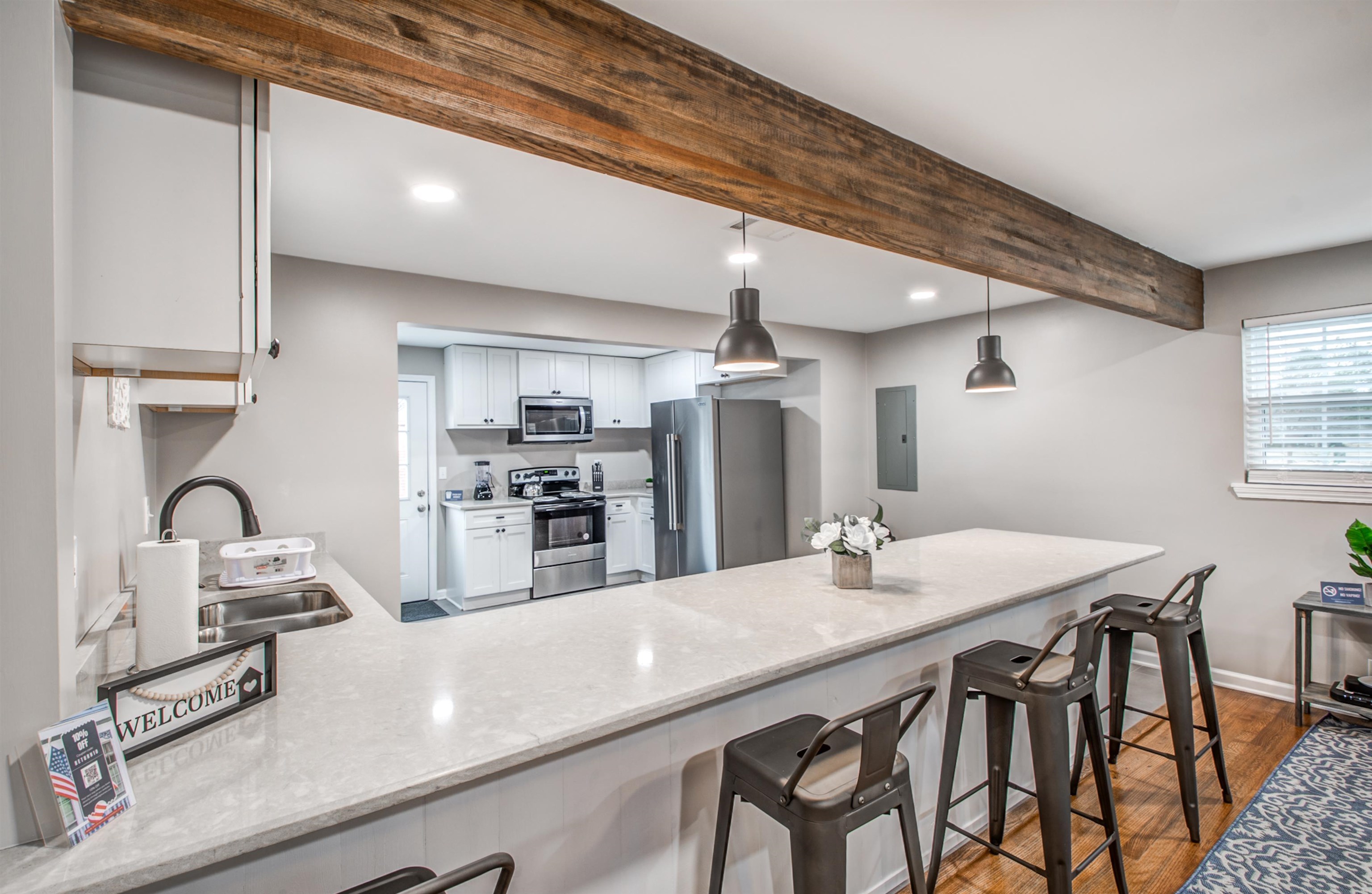 1277 Wellsville Road Memphis, TN 38117 - Photo 15 of 39 Kitchen featuring stainless steel appliances, dark wood-style floors, white cabinets, pendant lighting, and a breakfast bar