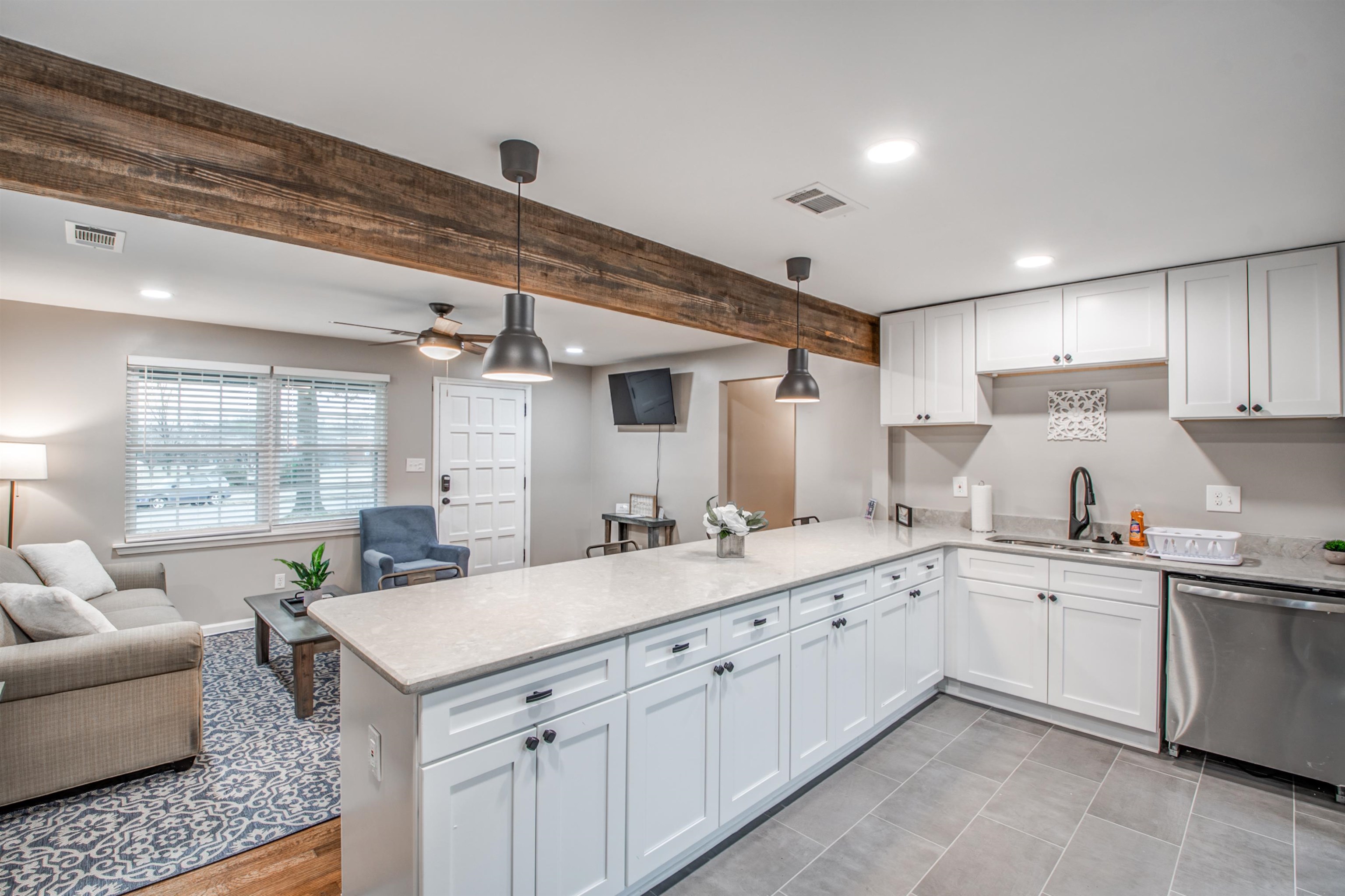 1277 Wellsville Road Memphis, TN 38117 - Photo 38 of 39 Kitchen featuring white cabinetry, dishwasher, open floor plan, light stone countertops, and beam ceiling