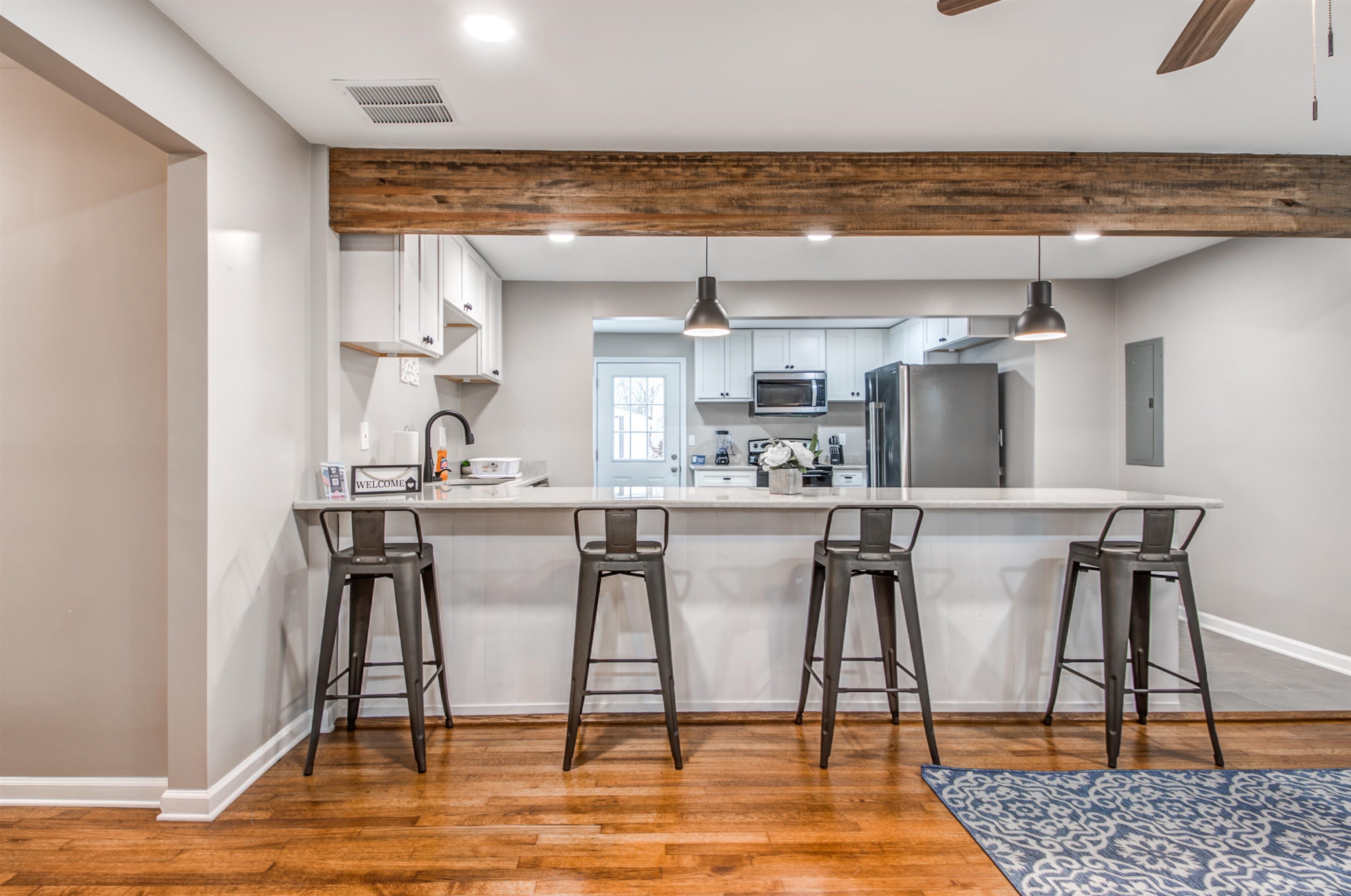 1277 Wellsville Road Memphis, TN 38117 - Photo 8 of 39 Kitchen featuring white cabinetry, a breakfast bar area, a peninsula, stainless steel appliances, and beamed ceiling
