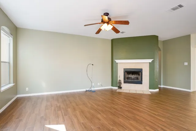 a view of empty room with fireplace and wooden floor