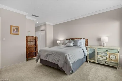 a spacious bedroom with a bed and a lamp on a dresser