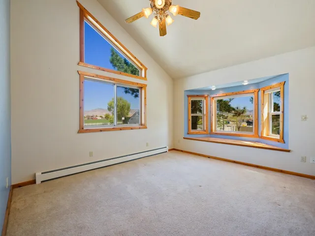 an empty room with windows and chandelier fan