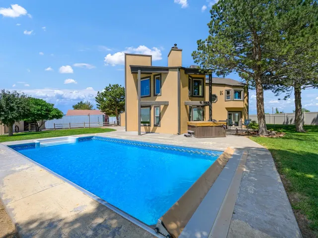 a view of pool with lawn chairs and large trees