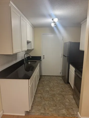 a kitchen with a sink a refrigerator and cabinets