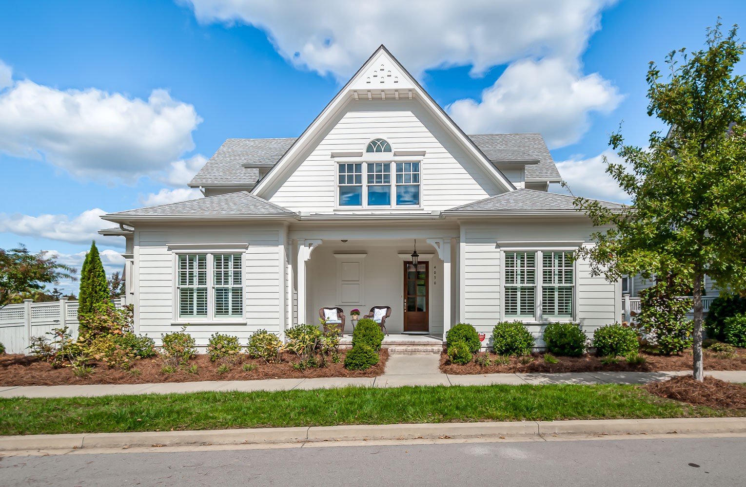 a view of a white house next to a yard with palm trees