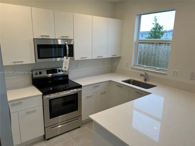 a kitchen with stainless steel appliances granite countertop a stove a sink and a white cabinets