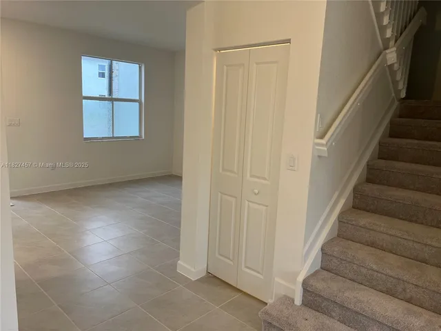 a view of an empty room with stairs and a window