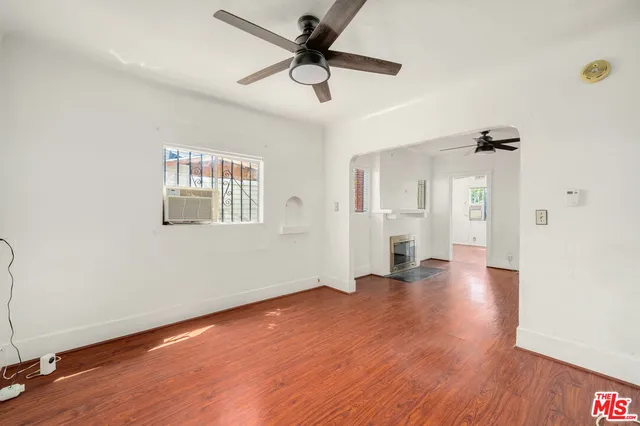 a view of an empty room with window and wooden floor