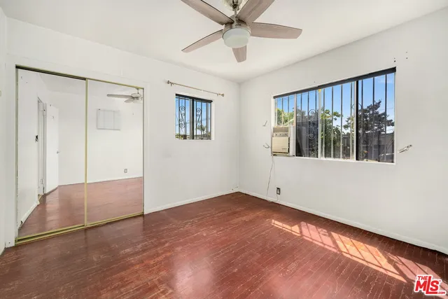 a view of empty room with wooden floor and ceiling fan