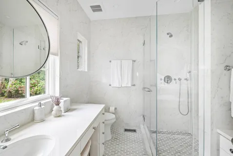 a bathroom with a granite countertop sink a toilet and shower