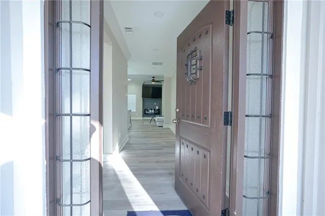 a view of a hallway with wooden floor and a bathroom