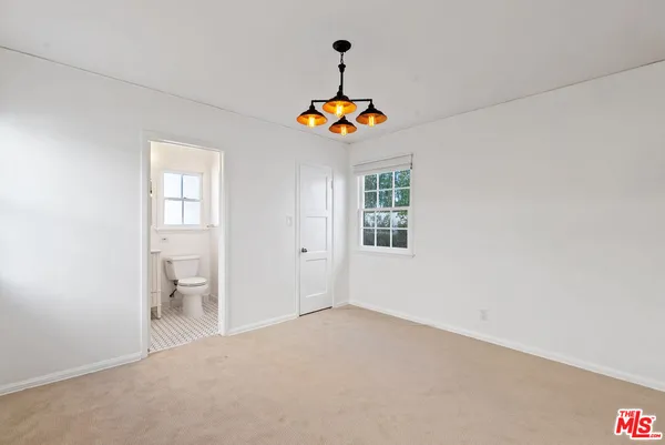 an empty room with windows and a chandelier fan