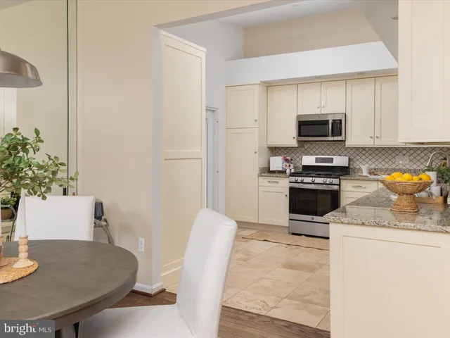 a kitchen with stainless steel appliances granite countertop a stove a sink a microwave a dining table and chairs