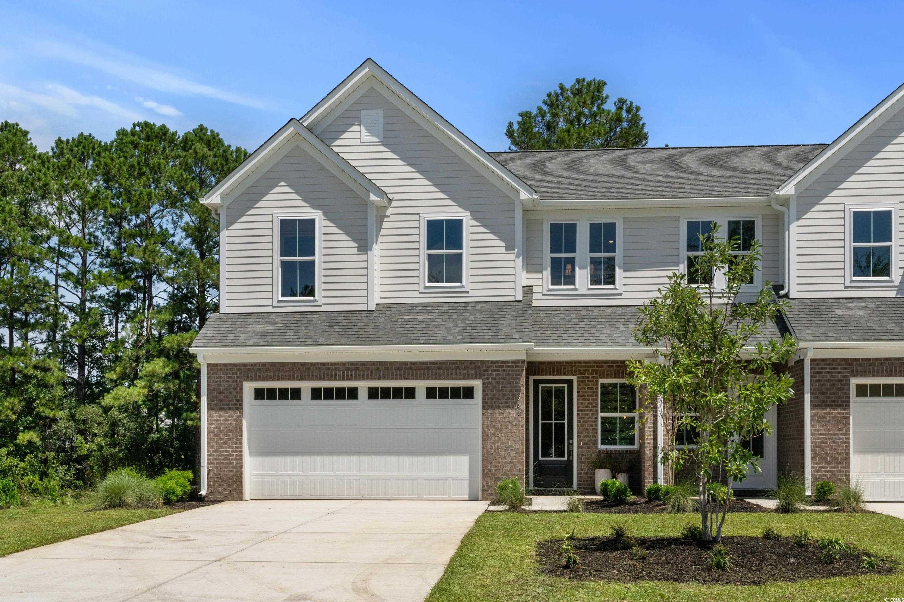 View of front of home featuring brick siding, a shingled roof, driveway, and a garage
