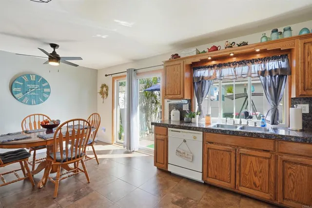 a dining hall with stainless steel appliances granite countertop a stove a sink a rug with a dining table and chairs